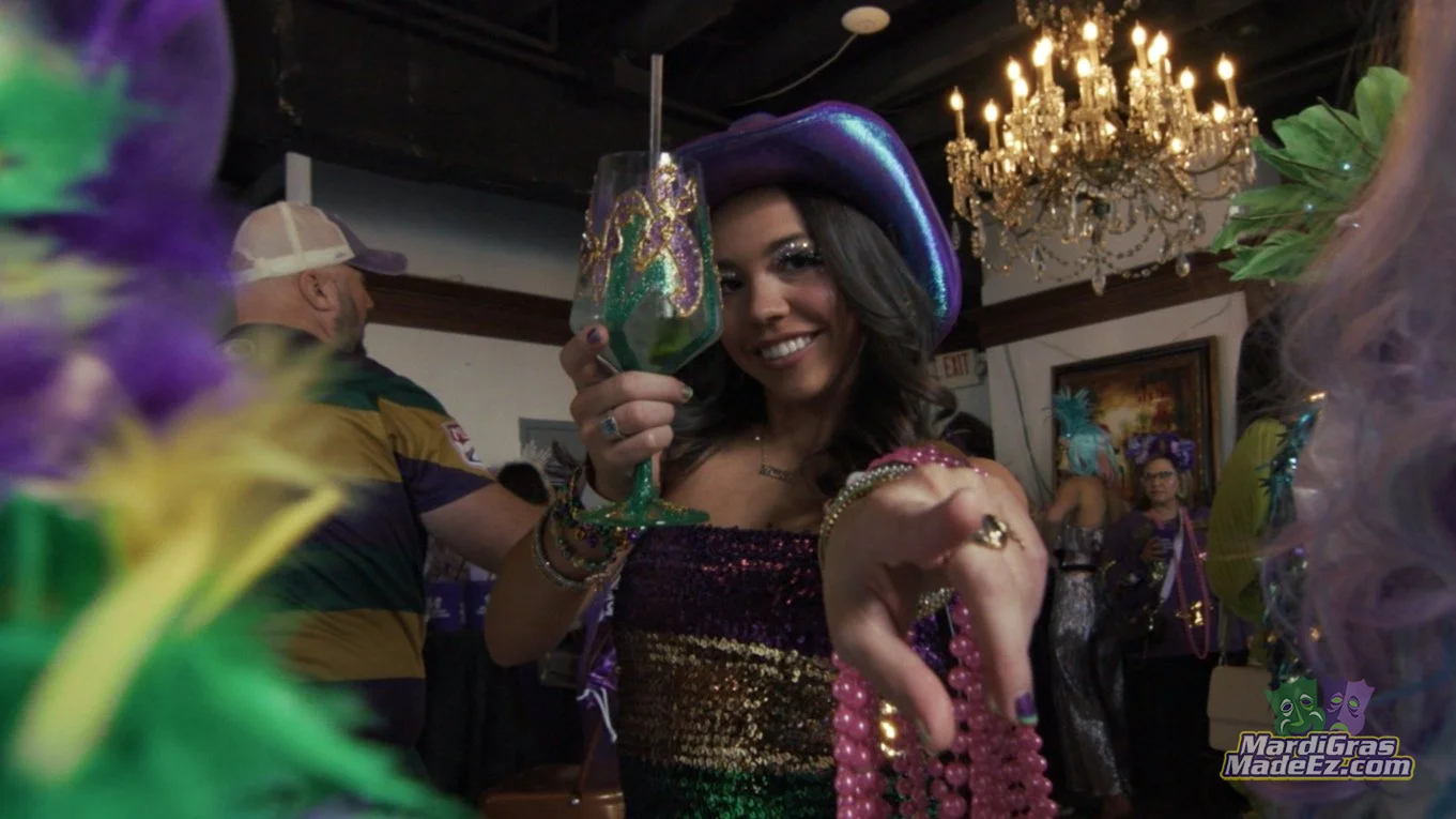 A guest raising a decorated cup during a Mardi Gras celebration