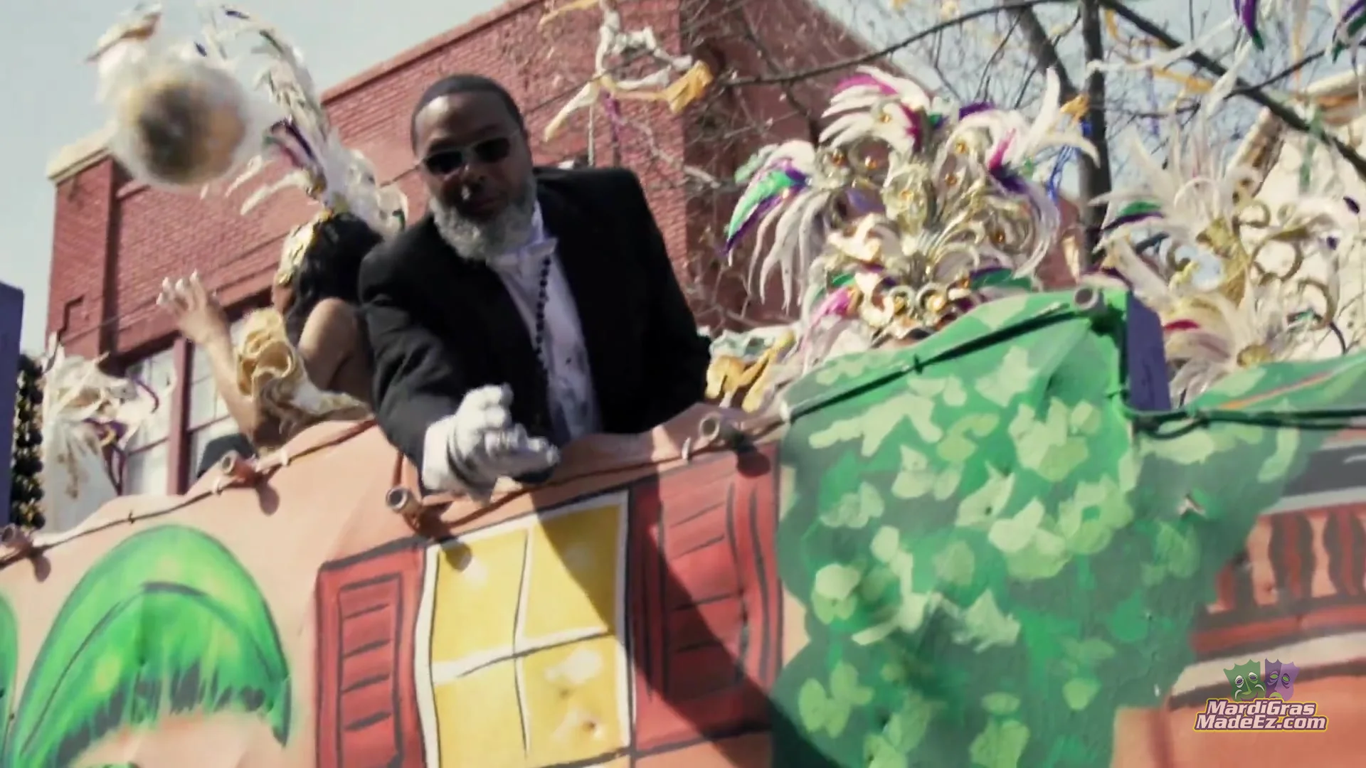 A float rider in white gloves tossing beads to the crowd