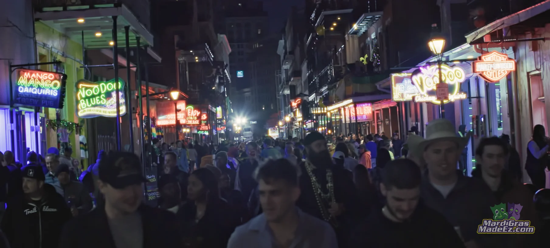 A crowd filling a neon-lit New Orleans street at night